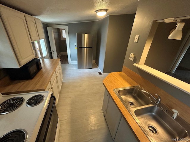 7 E Noble Ave, Monroe, MI 48162 - kitchen with butcher block countertops, freestanding refrigerator, black microwave, a textured ceiling, and electric range