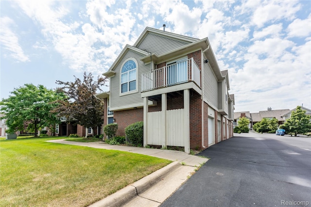 2165 Leighton Dr, Shelby Twp, MI 48317 - view of front facade featuring brick siding, a balcony, an attached garage, asphalt driveway, and a front yard