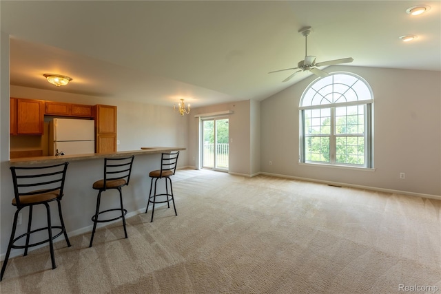 2165 Leighton Dr, Shelby Twp, MI 48317 - kitchen with freestanding refrigerator, a kitchen breakfast bar, brown cabinetry, light colored carpet, and a chandelier