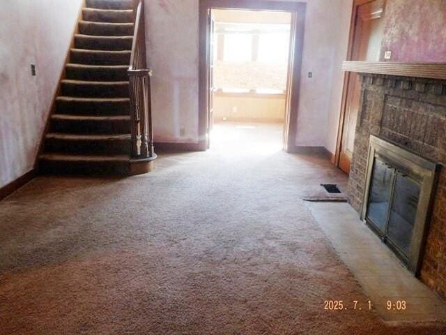 2535 Gull Rd, Kalamazoo, MI 49048 - unfurnished living room featuring carpet flooring, a glass covered fireplace, and stairway