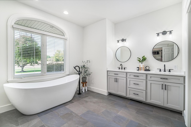 3603 Elk Ct, Zeeland, MI 49464 - bathroom with double vanity, a freestanding bath, recessed lighting, and stone finish flooring