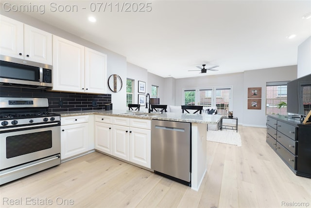 105 S 2nd St, Brighton, MI 48116 - kitchen featuring appliances with stainless steel finishes, a peninsula, light wood-style flooring, ceiling fan, and white cabinetry