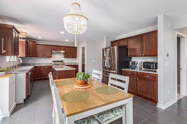 5775 Libby Ct, Dexter, MI 48130 - kitchen with stainless steel appliances, dark tile patterned floors, under cabinet range hood, recessed lighting, and a chandelier