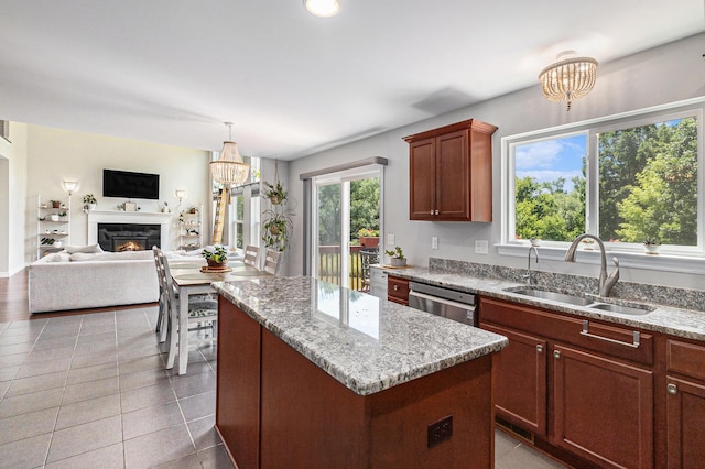 5775 Libby Ct, Dexter, MI 48130 - kitchen featuring a center island, stainless steel dishwasher, light stone countertops, and a warm lit fireplace