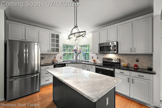 3066 Waldon Park Dr, Orion, MI 48359 - kitchen featuring stainless steel appliances, a center island, light wood finished floors, glass insert cabinets, and dark stone counters