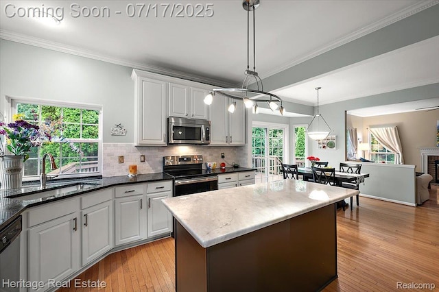 3066 Waldon Park Dr, Orion, MI 48359 - kitchen with stainless steel appliances, decorative backsplash, crown molding, hanging light fixtures, and light wood finished floors