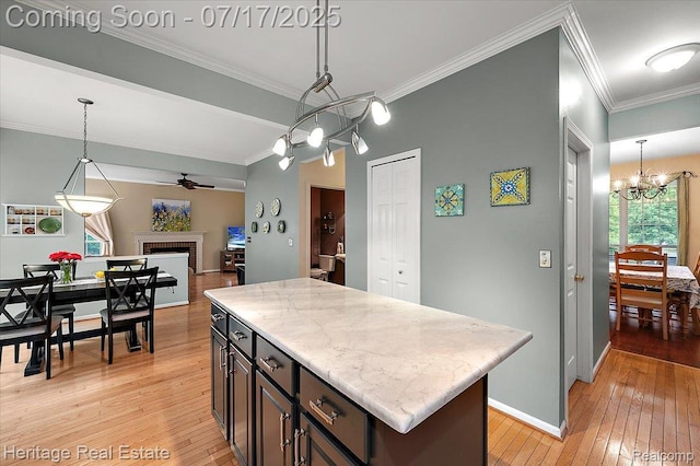 3066 Waldon Park Dr, Orion, MI 48359 - kitchen with a chandelier, light wood-type flooring, a ceiling fan, a fireplace, and crown molding