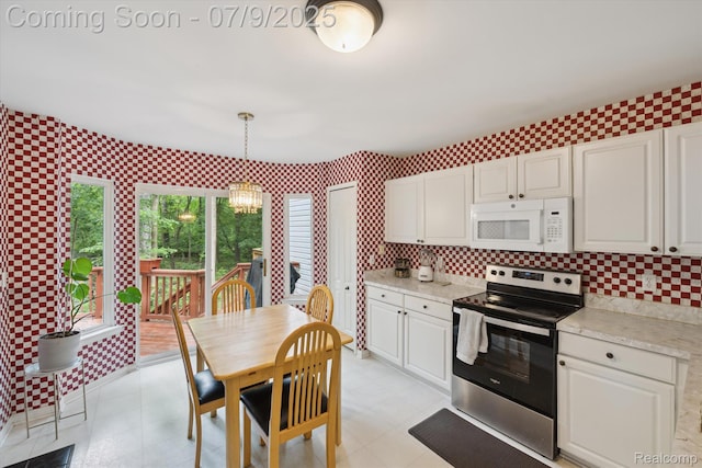 682 Chestnut Dr, Wixom, MI 48393 - kitchen with stainless steel electric range, white microwave, white cabinets, decorative light fixtures, and a chandelier