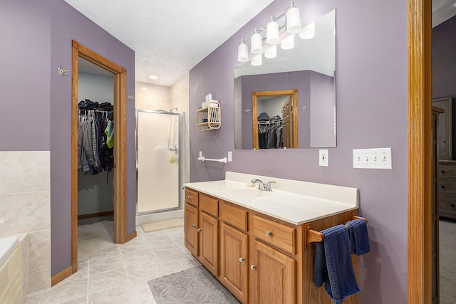 6177 Heathcross Dr, Hudsonville, MI 49426 - bathroom featuring a walk in closet, vanity, a stall shower, tile patterned flooring, and a bathtub