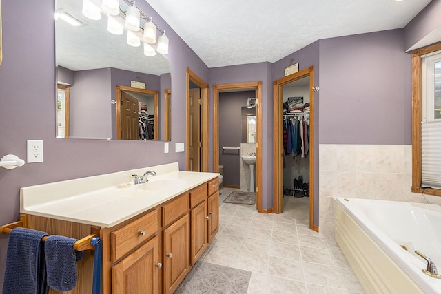 6177 Heathcross Dr, Hudsonville, MI 49426 - bathroom featuring vanity, a walk in closet, a garden tub, and tile patterned flooring