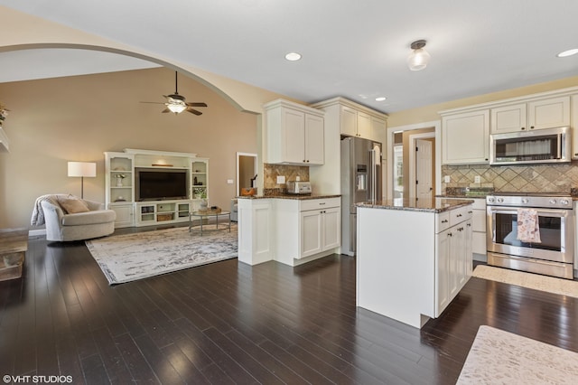 6044 Wabash Ln, Stevensville, MI 49127 - kitchen with stainless steel appliances, dark stone countertops, ceiling fan, backsplash, and arched walkways