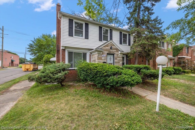 18714 Appoline St, Detroit, MI 48235 - view of front facade with a chimney, a front lawn, brick siding, and stone siding