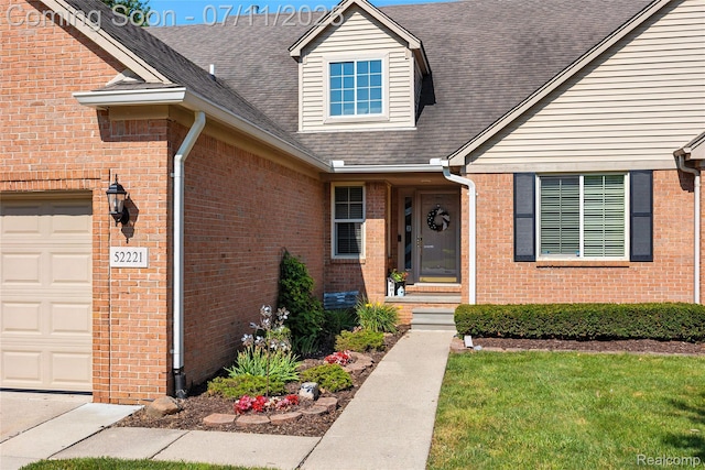 52221 Giuliano Ln, Macomb, MI 48042 - property entrance featuring an attached garage, brick siding, and a shingled roof