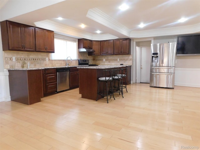2238 Nadine Dr, Sterling Heights, MI 48310 - kitchen featuring appliances with stainless steel finishes, under cabinet range hood, a raised ceiling, a breakfast bar area, and decorative backsplash
