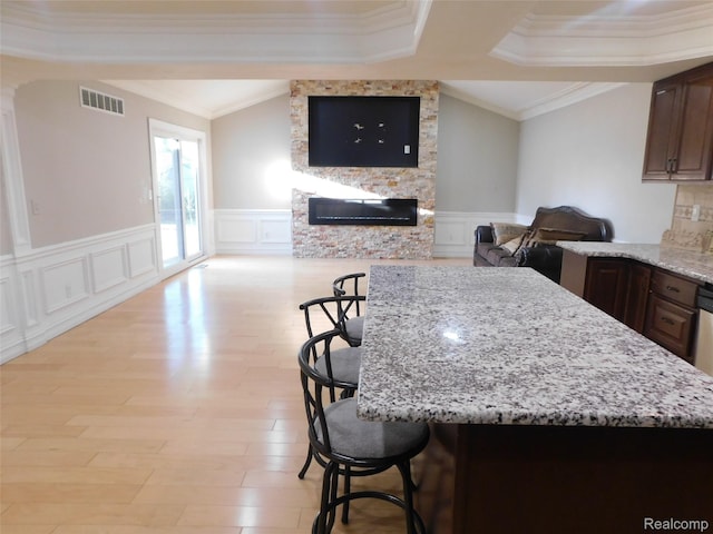 2238 Nadine Dr, Sterling Heights, MI 48310 - kitchen featuring a decorative wall, open floor plan, a fireplace, a kitchen bar, and crown molding