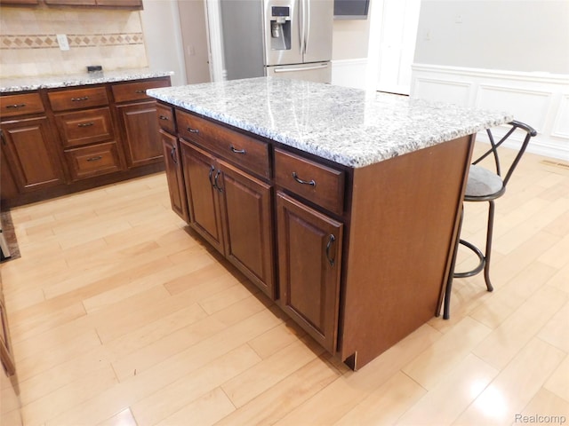 2238 Nadine Dr, Sterling Heights, MI 48310 - kitchen featuring freestanding refrigerator, a kitchen bar, decorative backsplash, wainscoting, and a kitchen island