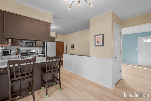 2958 Bluewater Ln SW, Grandville, MI 49418 - kitchen featuring appliances with stainless steel finishes, light wood-style flooring, decorative backsplash, and light countertops