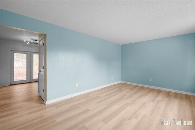 2958 Bluewater Ln SW, Grandville, MI 49418 - empty room with light wood-style floors, a textured ceiling, and french doors