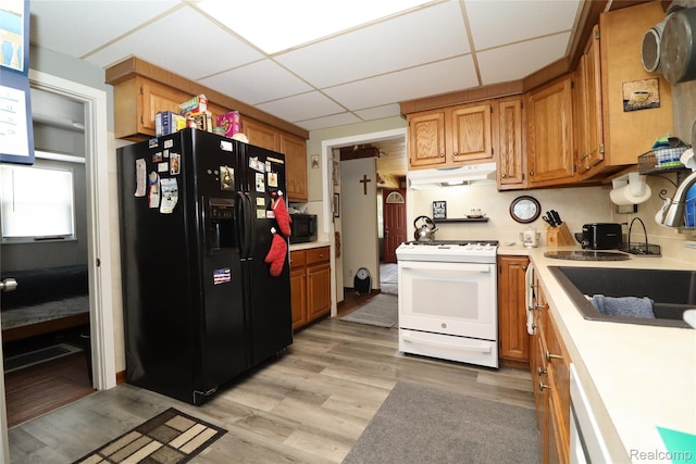 6500 Cooper St, Taylor, MI 48180 - kitchen featuring black appliances, under cabinet range hood, a paneled ceiling, light countertops, and light wood-type flooring