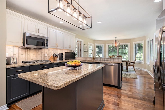 106 Kingsbury Ct, Battle Creek, MI 49015 - kitchen with stainless steel appliances, a peninsula, white cabinetry, wood finished floors, and decorative backsplash