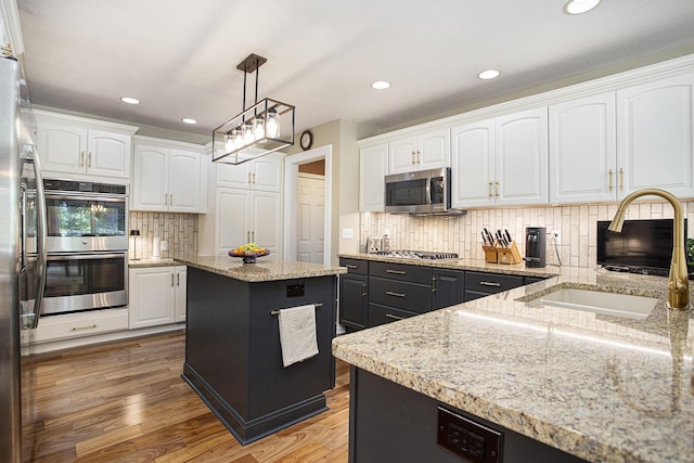 106 Kingsbury Ct, Battle Creek, MI 49015 - kitchen with stainless steel appliances, white cabinetry, decorative backsplash, light wood-style floors, and recessed lighting