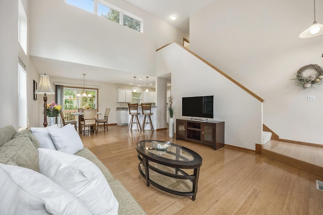 270 Silver Ridge Dr, Holland, MI 49424 - living room with light wood-type flooring, a towering ceiling, and a chandelier