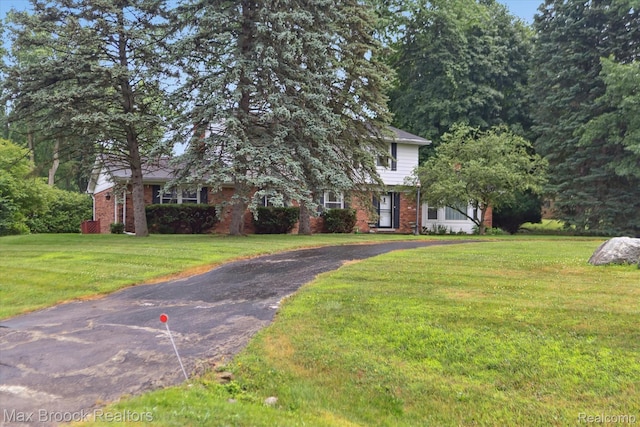 6810 Killarney Dr, Troy, MI 48098 - obstructed view of property featuring brick siding, a front lawn, and asphalt driveway