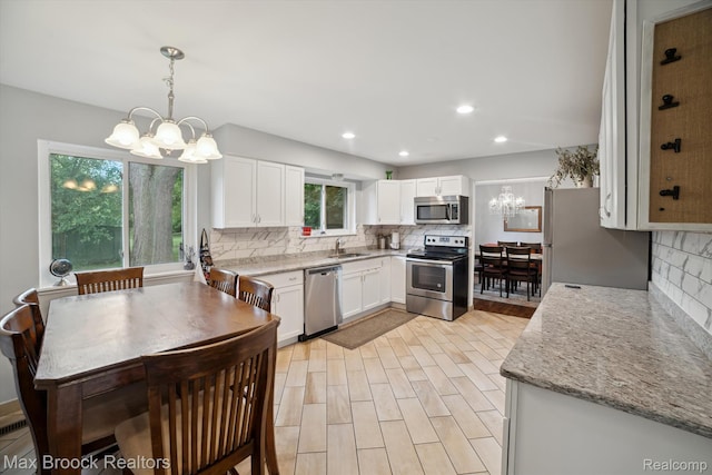 6810 Killarney Dr, Troy, MI 48098 - kitchen with stainless steel appliances, a chandelier, decorative backsplash, white cabinetry, and recessed lighting