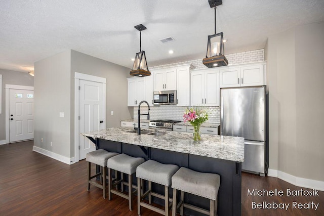 6725 Promenade St NE Unit 13, Rockford, MI 49341 - kitchen featuring appliances with stainless steel finishes, dark wood-style floors, a kitchen island with sink, and decorative backsplash
