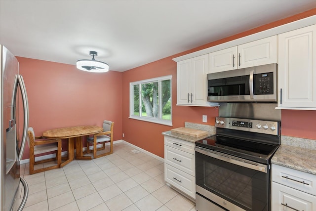 910 Newport Dr, Fenton, MI 48430 - kitchen featuring stainless steel appliances, white cabinets, light stone countertops, and light tile patterned flooring