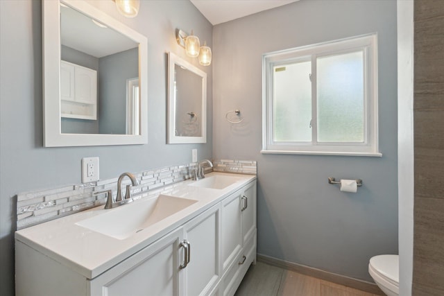 910 Newport Dr, Fenton, MI 48430 - bathroom featuring double vanity, backsplash, and wood finished floors