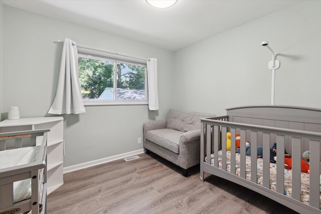 910 Newport Dr, Fenton, MI 48430 - bedroom featuring wood finished floors and a nursery area