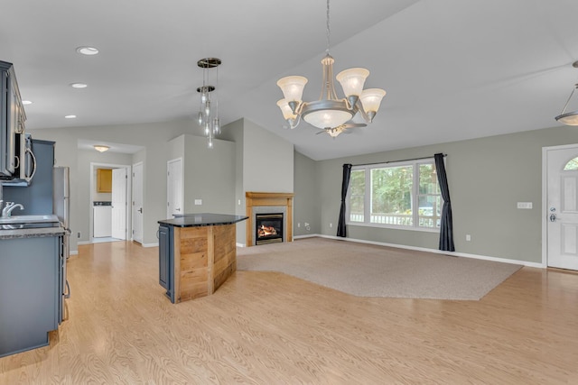 1615 Bunting Rd, Jackson, MI 49201 - unfurnished living room featuring lofted ceiling, light wood finished floors, a glass covered fireplace, a chandelier, and recessed lighting