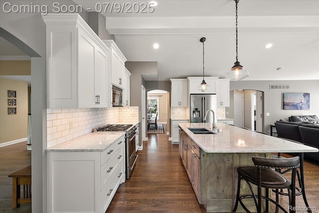 6591 Tree Knoll Dr, Troy, MI 48098 - kitchen with appliances with stainless steel finishes, arched walkways, tasteful backsplash, dark wood-style floors, and an island with sink