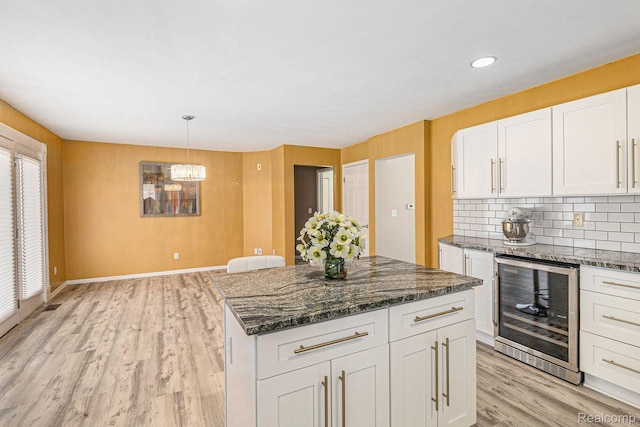 5103 Coachlight Dr, Fenton, MI 48430 - kitchen featuring wine cooler, light wood-style flooring, white cabinetry, a center island, and a chandelier