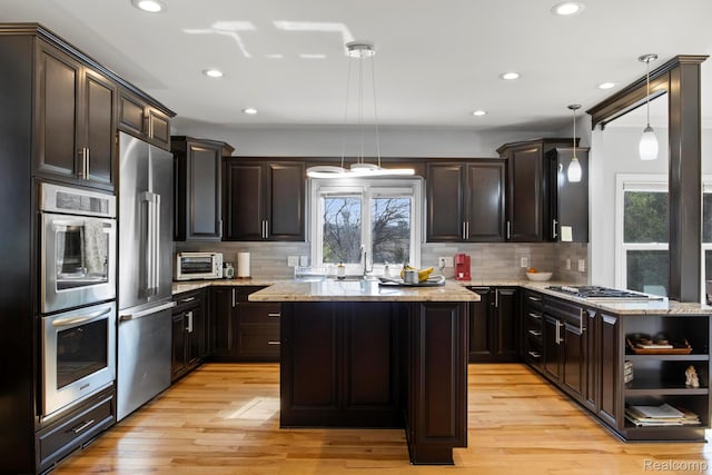 900 Mcdonald Dr, Northville, MI 48167 - kitchen featuring stainless steel appliances, a center island, decorative backsplash, open shelves, and light stone counters