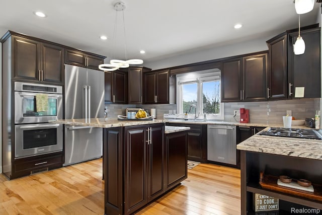 900 Mcdonald Dr, Northville, MI 48167 - kitchen featuring stainless steel appliances, dark brown cabinets, light stone countertops, light wood-style flooring, and backsplash