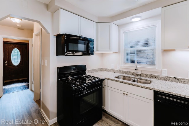 16219 Normandy St, Detroit, MI 48221 - kitchen featuring black appliances, light stone countertops, white cabinetry, light wood-style floors, and arched walkways