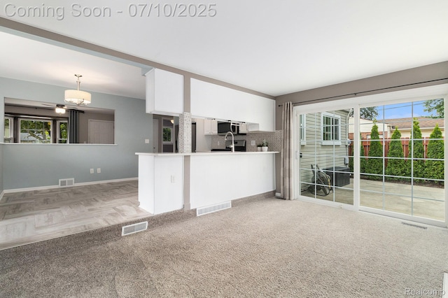 39408 Atkinson Dr, Sterling Heights, MI 48313 - kitchen with white cabinets, stainless steel microwave, decorative backsplash, decorative light fixtures, and light countertops