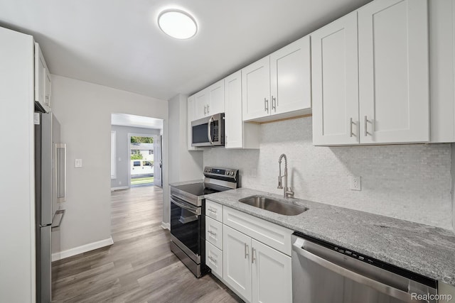 2245 Spring Hill Ave, Inkster, MI 48141 - kitchen with stainless steel appliances, wood finished floors, tasteful backsplash, white cabinets, and light stone countertops