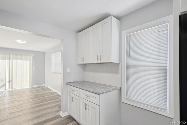 2245 Spring Hill Ave, Inkster, MI 48141 - kitchen with white cabinets, light wood-type flooring, backsplash, and light stone counters
