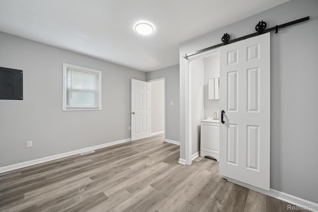 2245 Spring Hill Ave, Inkster, MI 48141 - unfurnished bedroom featuring electric panel, a barn door, and wood finished floors