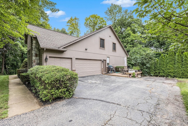 9780 Oak Valley Dr, Clarkston, MI 48348 - view of side of home featuring a shingled roof, asphalt driveway, and stone siding