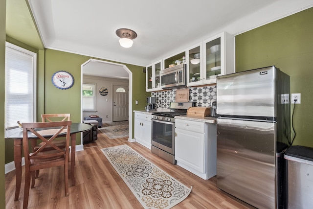 352 W Tacoma St, Clawson, MI 48017 - kitchen featuring appliances with stainless steel finishes, arched walkways, white cabinetry, backsplash, and glass insert cabinets
