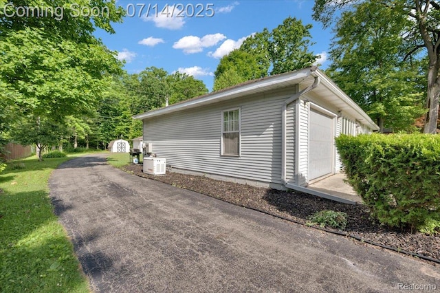 3117 Maumee Trl, Clyde, MI 48049 - view of side of home with a garage, a storage unit, and a lawn