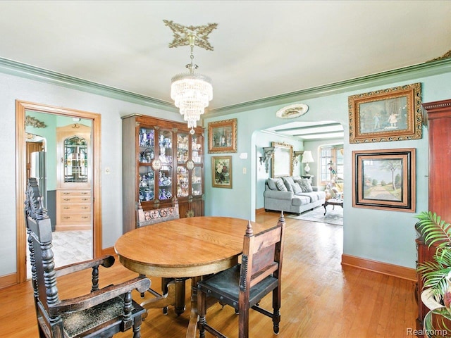 1313 Wall St, Port Huron, MI 48060 - dining space featuring ornamental molding, a chandelier, arched walkways, and light wood finished floors