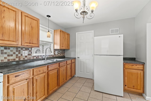 14268 Trenton Rd, Southgate, MI 48195 - kitchen with freestanding refrigerator, dark countertops, backsplash, light tile patterned floors, and a chandelier