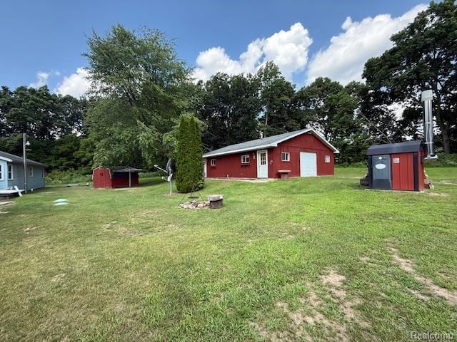 3103 Roush Rd, Hastings, MI 49058 - view of grassy yard featuring a detached garage, a storage shed, and view of wooded area