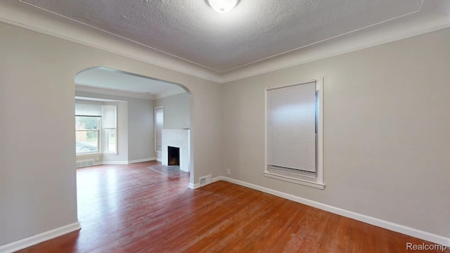 10800 Stratman St, Detroit, MI 48224 - unfurnished living room with arched walkways, wood finished floors, a fireplace with flush hearth, a textured ceiling, and crown molding
