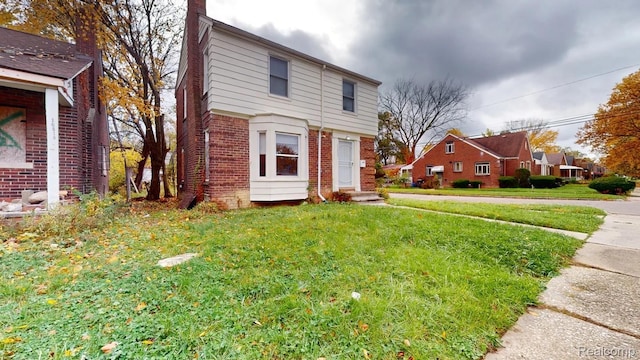 10800 Stratman St, Detroit, MI 48224 - view of front of house with brick siding, a chimney, a front yard, and entry steps